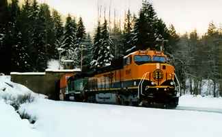 Emerging from West portal of 8 mile long new Cascade Tunnel, new BNSF GE locomotive 1047, a C44.9W leads a double stack in December 1996.
